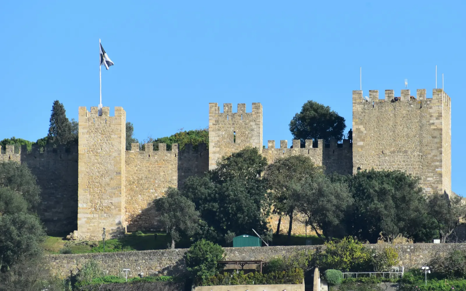The crenellated walls and towers of Castelo de São Jorge under a blue sky